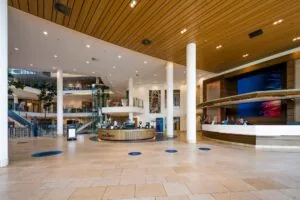 Moderne ontvangsthal van het gebouw aan de Laan van Langerhuize met receptiebalie, koffiebar en glazen lift.